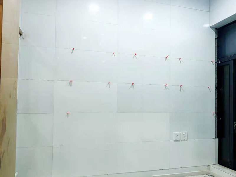 墻磚鋪貼施工：基層處理：保持墻面的平滑，踢平表面凹凸不平的位置或用1:3比例的水泥漿抹平，用鐵絲擦掉殘留的灰塵、油漬、砂漿等。 找標高、彈線：根據水平控制線和設計圖紙劃出標高，再拋出十字線并保持墻面一線和地面一線垂直。 預鋪：在圖紙設計要求的基礎上，嚴格挑選墻磚的色彩、紋理等，然后進行預鋪，對于預鋪效果中可能出現的紋理、尺寸、色差進行調整、更換，直到達到最佳效果。 貼磚：貼磚選用1：3比例的干硬性水泥砂漿，砂漿厚度2cm左右。鋪貼前將墻磚背面濕潤，正面保持干燥。把墻磚輕輕地放在水泥砂漿上，用手錘輕敲瓷磚表面直至緊密平整即可。 勾縫、擦縫：在貼完磚24小時后進行勾縫工作，采用同一品種的水泥漿或專用填縫劑進行空隙填補，使墻磚最終緊密嚴實，最后再擦凈多余的水泥或填縫劑。